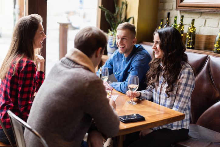 Friends socializing over white wine, smiling, sitting in restaurant