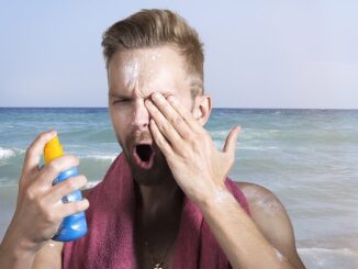 Mann sprueht sich Sonnencreme ins Auge