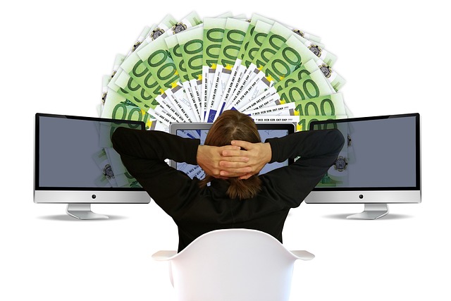 Person vor Computerschirmen und 100-Euro-Fächer | Person vor Computerschirmen und 100-Euro-Fächer