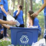 Menschen sammeln Plastikmüll in eine blaue Kiste