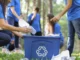 Menschen sammeln Plastikmüll in eine blaue Kiste