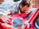 Mann küust sein rotes Auto