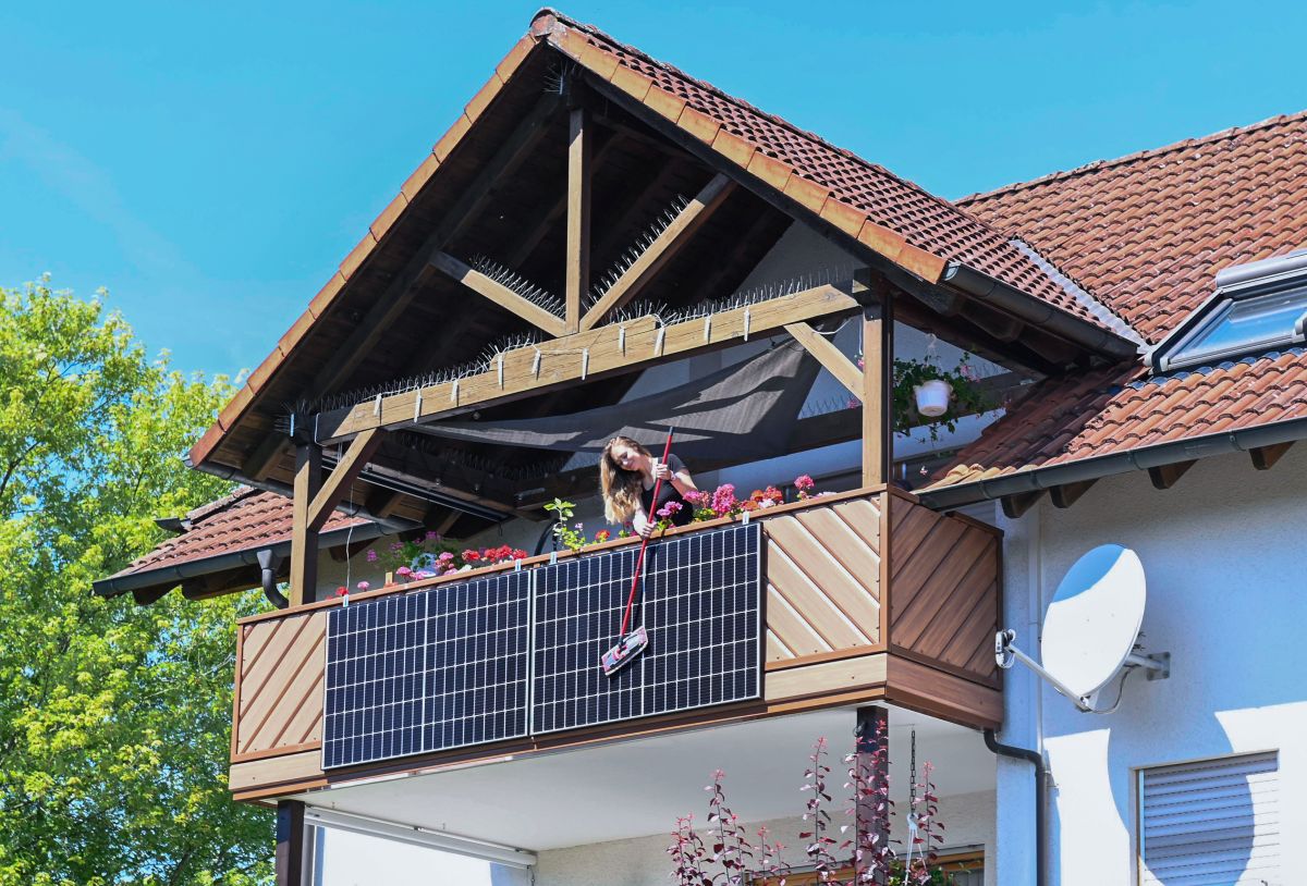 Frau putzt Solaranlage am Balkon eines Hauses | Frau putzt Solaranlage am Balkon eines Hauses