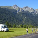 Geparktes Wohnmobil und wandernde Menschen vor hohem Gebirge