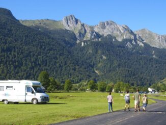 Geparktes Wohnmobil und wandernde Menschen vor hohem Gebirge