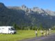 Geparktes Wohnmobil und wandernde Menschen vor hohem Gebirge