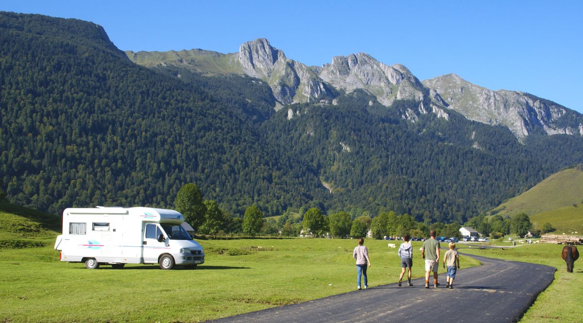 Geparktes Wohnmobil und wandernde Menschen vor hohem Gebirge | Geparktes Wohnmobil und wandernde Menschen vor hohem Gebirge