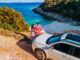 Pärchen mit dem Auto oberhalb einer Strandbucht