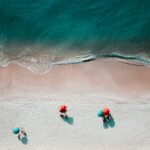 Sandstrand mit Sonnenschirmen von oben