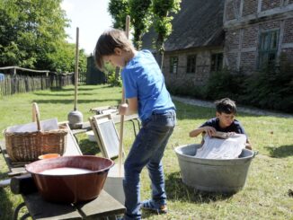 Kinder probieren beim Sommerspaß bäuerliches Leben im letzten Jahrhundert