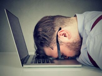 erschöpfter Mann liegt auf dem Laptop