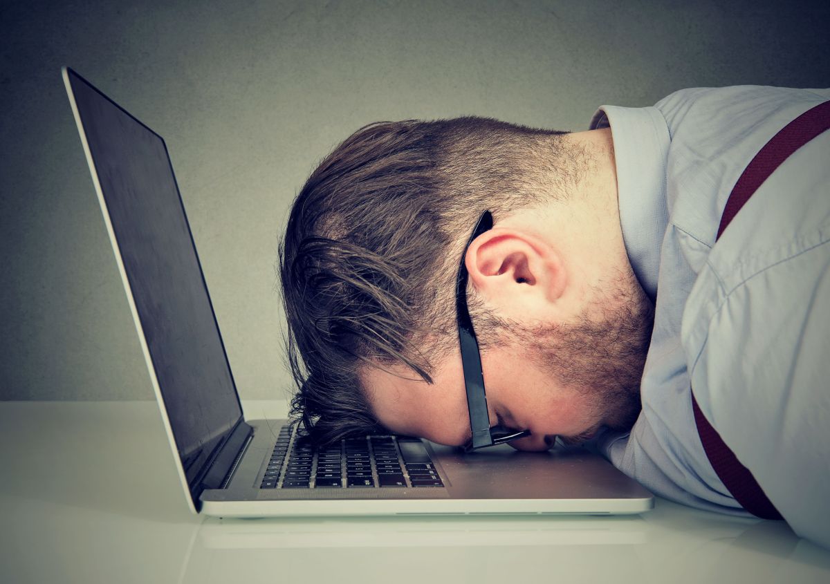 erschöpfter Mann liegt auf dem Laptop
