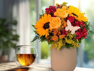 Blumenstrauss in Vase und ein Glas Tee
