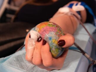 Hand mit Erdball und Transfusionsschläuchen