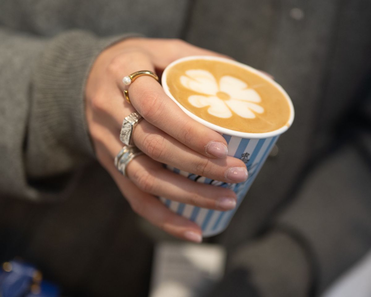 Kaffee-Design in guten Händen | hamburg040 Elegante Frauenhand hält Kaffeebecher mit Kleeblatt aus Milchschaum