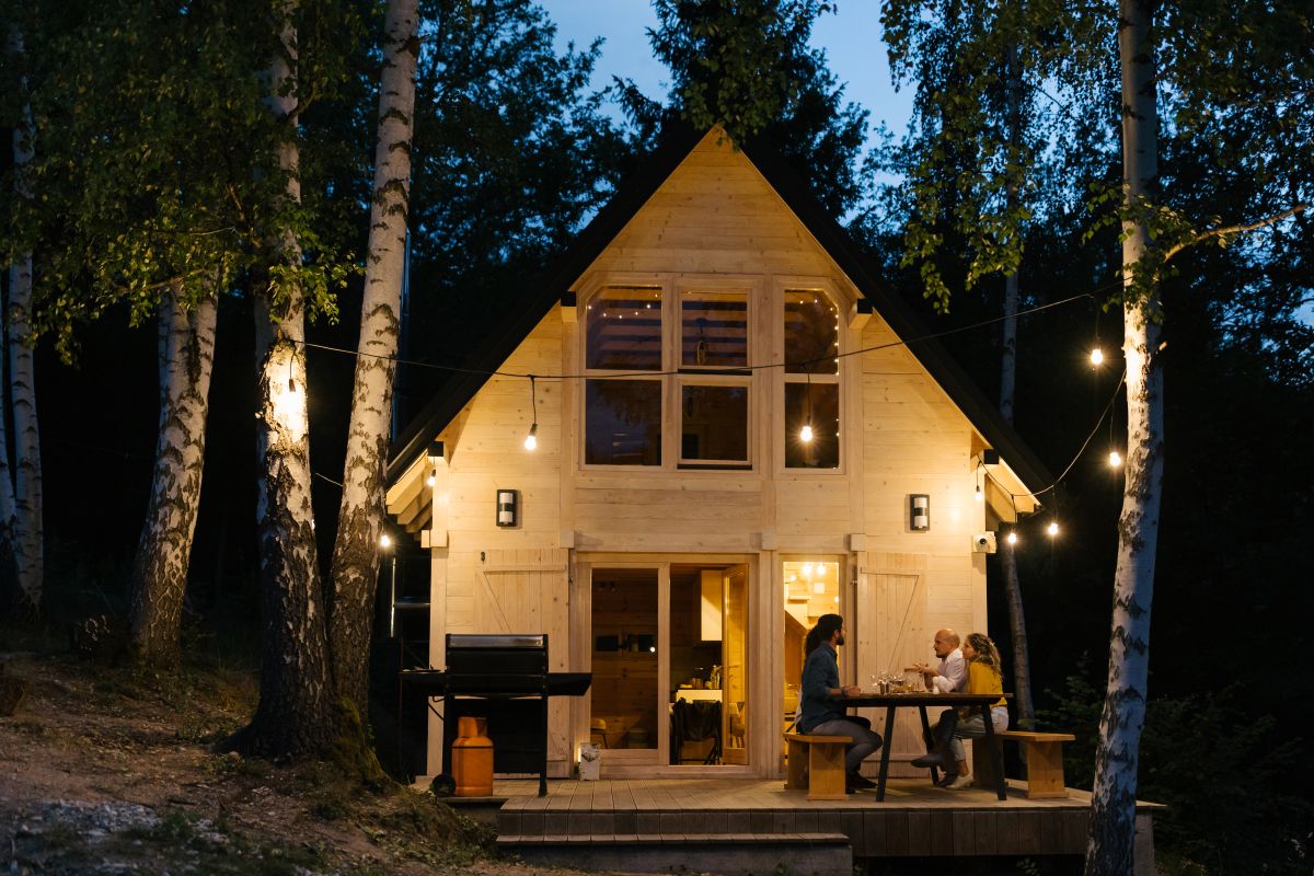Leute sitzen nachts vor beleuchtetem Ferienhaus