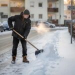 Mann schiebt den Gehweg vom Schnee frei