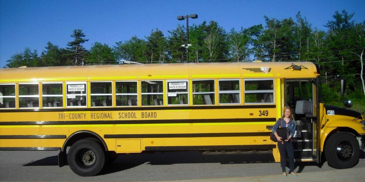 Schülerin vor Schulbus in Kanada