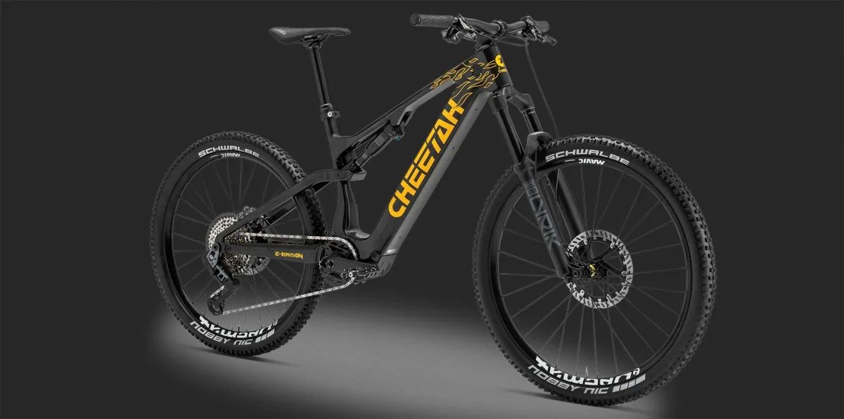 Full-suspension black mountain bike with yellow branding on the downtube, thick knobby tires, on a dark background.
