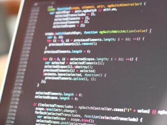 Close-up of a monitor displaying colorful JavaScript code with syntax highlighting.
