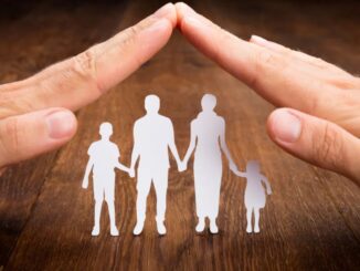 Hände über Scherenschnittfamilie bilden ein Dach