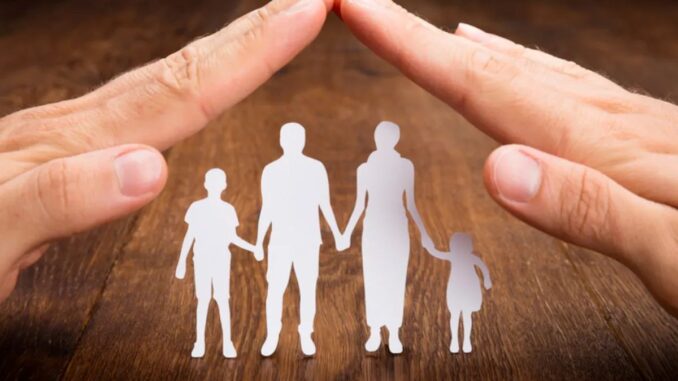 Hände über Scherenschnittfamilie bilden ein Dach