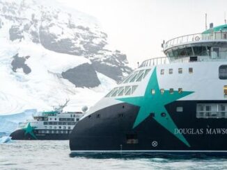 Expedition cruise ship in icy waters with snow-covered mountains; hull shows the name Douglas Mawson.