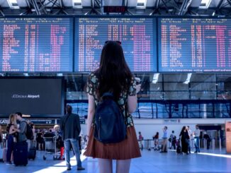 Frau am Flughafen blickt auf die Anzeigetafeln