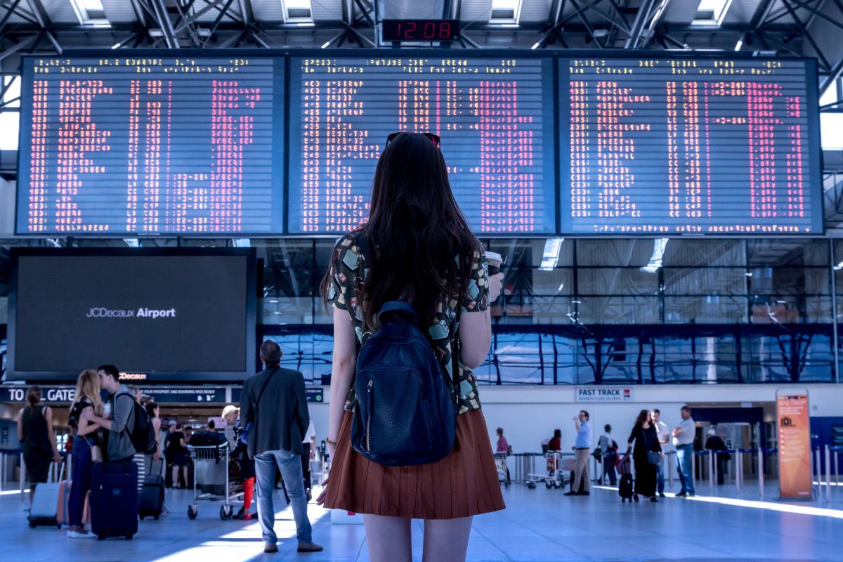 Frau am Flughafen blickt auf die Anzeigetafeln