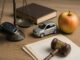 Autoschlüssel, Auto, Apfel und Buch auf dem Richtertisch