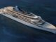 Aerial view of a large white luxury yacht cruising on dark blue ocean, with multiple sun decks and a visible helipad on the bow and stern areas.