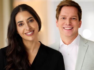 Two professionals, a woman in a black top and a man in a light suit, smiling for a team photo.