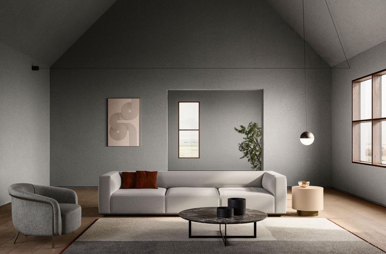 : Ein Sofa in der Mitte des Raums auf einem quadratischen Teppich, dazu Beistelltische und ein Sessel